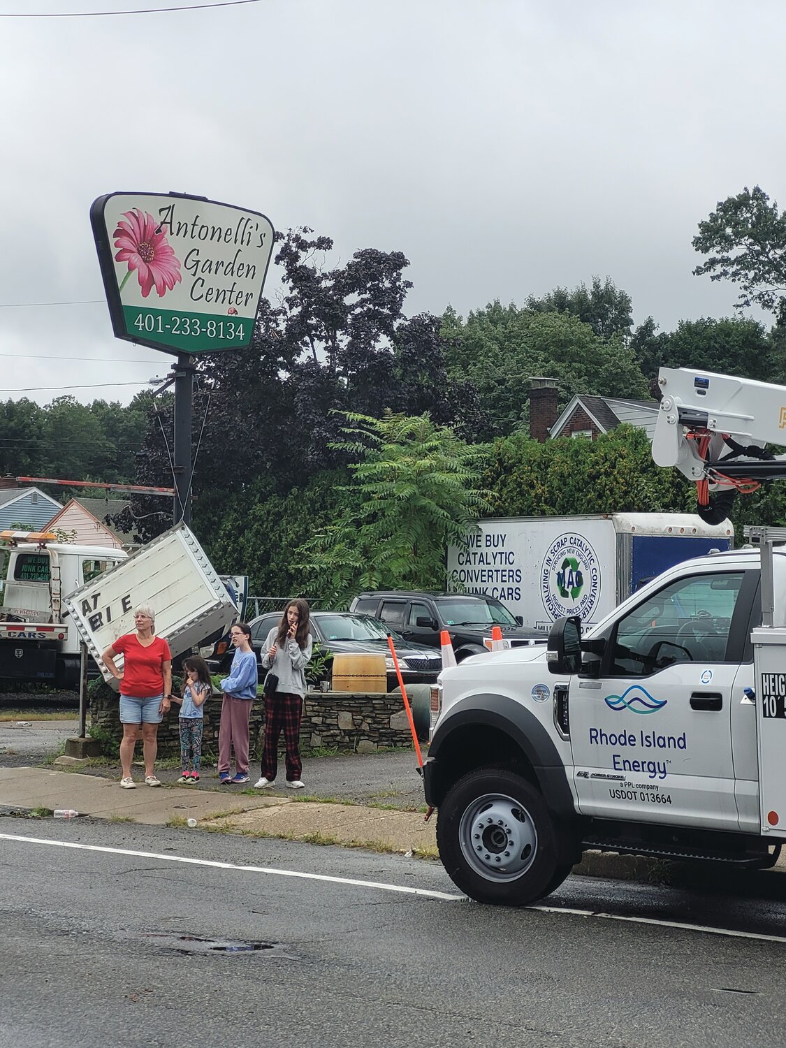 SIGNS OF DAMAGE: Residents stand along George Waterman Road looking down Amber Street at damage caused by Friday morning’s storm. A sign fell from the business behind them. Workers worked at clearing fallen trees to clear an exit for trapped Amber Street residents.